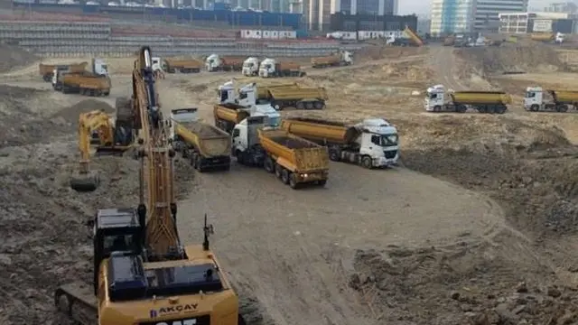 Geniş hafriyat sahasında ekskavatörlerle birlikte çalışan damperli kamyonlar